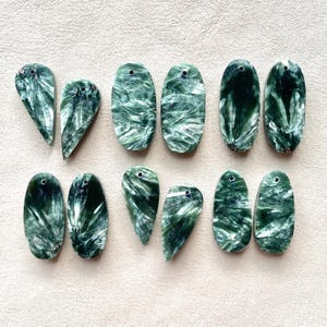 Peut inclure: Dix cabochons de pierres précieuses vertes et blanches, certains de forme ovale et d'autres en forme de larme. Les pierres ont un motif unique et tourbillonnant.