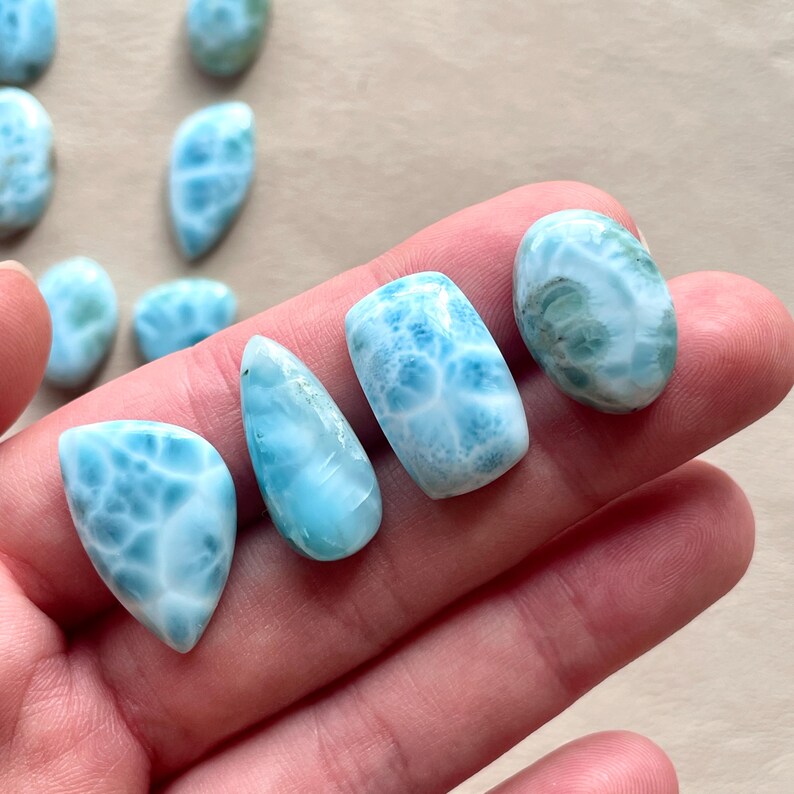 May include: Five blue and white cabochon gemstones with a swirling pattern. The stones are various shapes and sizes.