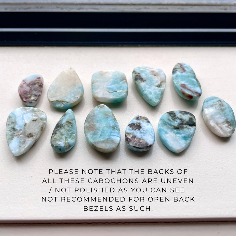 May include: Ten cabochons of blue, white, and grey gemstone with brown and red inclusions. The stones are uneven and not polished on the back.