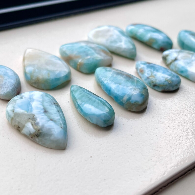 May include: A collection of ten teardrop-shaped blue and white gemstone cabochons. The stones have a cloudy, marbled appearance with a smooth, polished finish.