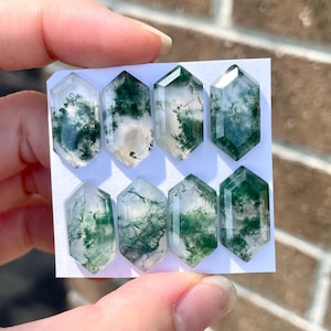 May include: Six green and white moss agate cabochons in a hexagonal shape, arranged in two rows on a white card.