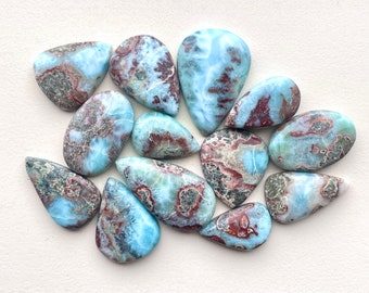 Puede incluir: Una colección de 12 cabujones de piedra preciosa en forma de lágrima, pulidos, azules, verdes y marrones. Las piedras tienen un patrón veteado y en espiral.