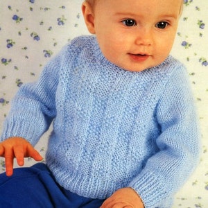 May include: A light blue knitted sweater with a cable knit pattern. The sweater is worn by a baby.
