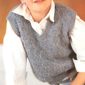 May include: A grey knitted waistcoat with a V-neck. The waistcoat has a textured pattern and is worn over a white button-down shirt.