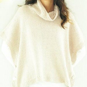 May include: A white knitted poncho with a cowl neck and button details.