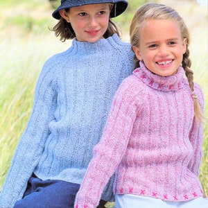 May include: Two girls wearing knitted sweaters. The girl on the left is wearing a light blue sweater and a black hat. The girl on the right is wearing a pink sweater.