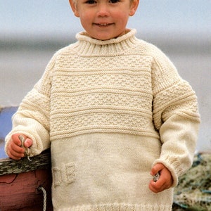 May include: A white knitted sweater with a high neck and a textured pattern. The sweater has a pocket on the front.