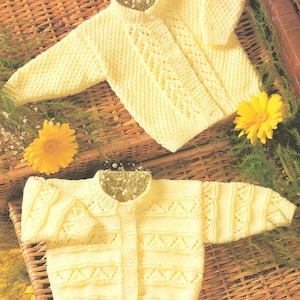 May include: Two yellow knitted baby cardigans with button closures. The cardigans have a delicate cable knit pattern.