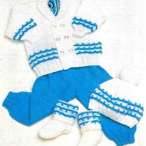 Puede incluir: Un cárdigan de punto blanco para bebé con ribetes azules, pantalones de punto azul a juego, botines de punto blanco y un gorro de punto blanco con ribetes azules.