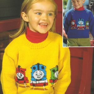 Puede incluir: Dos niños con suéteres de punto amarillo y azul con Thomas la locomotora y sus amigos bordados en la parte delantera.