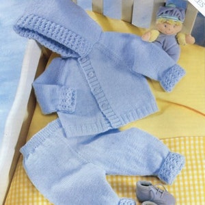 May include: A knitted baby outfit in light blue with a hooded jacket and matching trousers. The outfit is laid out on a yellow and white checked fabric.