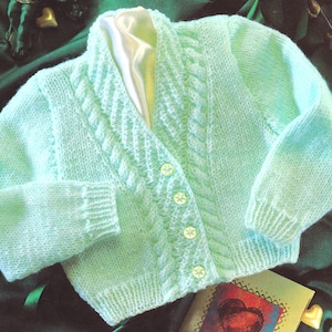 Op de afbeelding: Een lichtgroene gebreide cardigan met een kabelbreipatroon en knoopsluiting.