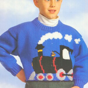 Könnte beinhalten: Ein blauer Strickpullover mit einem Zugmotiv. Der Zug ist schwarz mit weißem Rauch und roten Rädern.