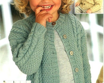 May include: A light green knitted cardigan with a cable knit pattern and button closure. The cardigan is shown being worn by a young child. The text "Sirdar" and "Includes Sizes for Baby" is visible on the image.