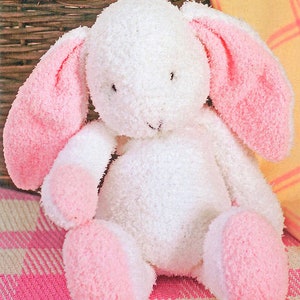 May include: A white plush bunny with pink ears and feet. The bunny is sitting on a pink and white checked blanket.