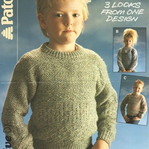 May include: A green knitted sweater with a crew neck and long sleeves. The sweater is shown on a young person. The image also shows three different ways to style the sweater. The text "3 looks from one design" is printed on the image.