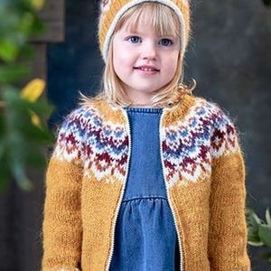Könnte beinhalten: Ein kleines Kind trägt eine gelbe und braune Strickjacke mit einem bunten geometrischen Muster und eine passende Strickmütze. Die Jacke hat einen Reißverschluss.