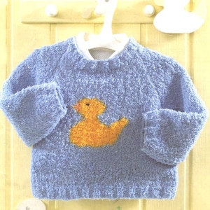 May include: A blue knitted baby sweater with a yellow duck applique on the front.
