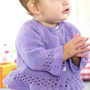 Könnte beinhalten: Ein lila gestrickter Cardigan mit Knopfleiste und Spitzenbesatz. Der Cardigan wird von einem Kind getragen.