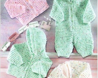 May include: A collection of hand-knitted baby clothes in soft pastel colors. The image features a pink cardigan, a green hooded jumpsuit, a green hooded jacket, and a cream-colored jacket. Decorative wooden train toys are scattered around the garments.
