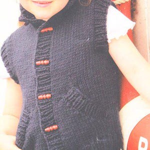 May include: A navy blue knitted vest with a shawl collar and a single pocket. The vest features four wooden toggle closures and is worn over a white shirt. The vest is a cozy, handmade garment.