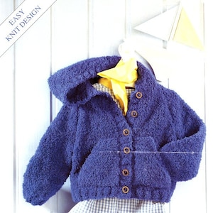 May include: A blue knitted hooded jacket with a pocket and button closure. The jacket is hanging on a white wooden door with a yellow scarf draped over it.