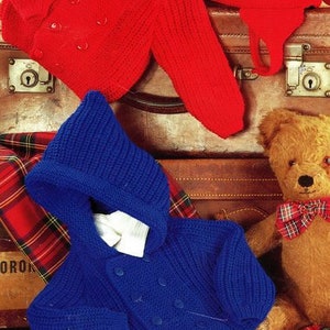May include: Two knitted baby sweaters, one red and one blue. The red sweater has a button closure and the blue sweater has a hood. A teddy bear is sitting on a plaid blanket.