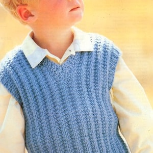 Puede incluir: Un chaleco azul tejido con cuello en V. El chaleco tiene una textura acanalada y lo lleva puesto un niño pequeño.