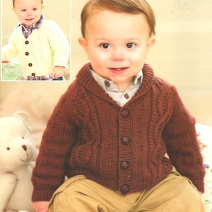 May include: A brown knitted cardigan with a collared neckline and button fastening. The cardigan is being worn by a young child with a white shirt underneath.