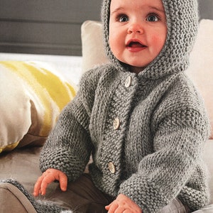 Op de afbeelding: Een grijze gebreide hooded cardigan met knopen, gedragen door een baby. De cardigan heeft een textuur gebreid patroon en is gemaakt van zacht garen.