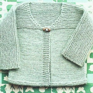 May include: A light green knitted cardigan with a button fastening. The cardigan has a V-neck and long sleeves.