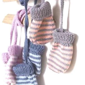 May include: A collection of knitted baby mittens in various colors, including pink, blue, and gray. The mittens are striped and attached to a string for easy hanging. They are displayed on a wooden branch against a white background.