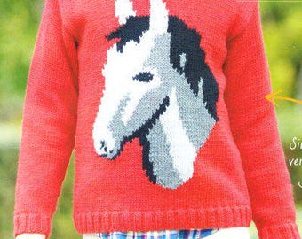 May include: A red knit sweater featuring a horse head design in white, gray, and black. The sweater has long sleeves and a ribbed hem. The person is wearing a plaid shirt underneath and white pants.