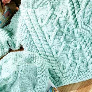Peut inclure: Un ensemble de tricot pour bébé en bleu clair composé d'un pull et d'un bonnet. Le pull est à col rond et le bonnet est de style béret simple.
