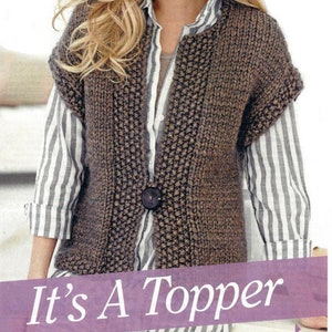 May include: A brown knitted sleeveless vest with a button closure. The vest is worn over a striped shirt. The text "It's A Topper" is displayed below the image.