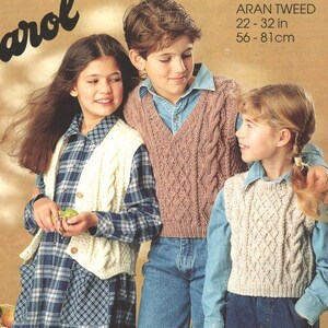 May include: Three children wearing knitted vests. The vests are white, pink, and cream with a cable knit pattern. The children are wearing blue jeans and plaid shirts. The text "ARAN TWEED 22-32 in 56-81 cm" is printed on the image.