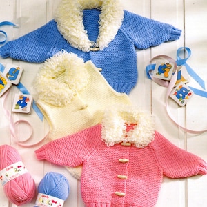 May include: Three knitted baby cardigans in blue, yellow, and pink with white fur trim collars. The cardigans have button closures.