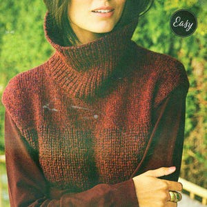 May include: A burgundy knitted turtleneck sweater with a ribbed texture. The sweater has a wide, folded collar and a loose fit.