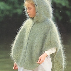 May include: A light green hooded poncho with a fuzzy texture. The poncho has a long, flowing design and a hood with a white trim.