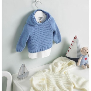 Peut inclure: Un pull à capuche en tricot bleu clair avec une chemise blanche à col en dessous, suspendu à un cintre blanc. Un pull à capuche en tricot de couleur crème est posé sur une surface blanche. Des jouets décoratifs en forme de voilier et d'animaux en peluche sont également présents.
