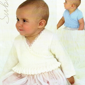 May include: A white knitted baby cardigan with a lace trim and a wrap-style closure. The cardigan has a ruffled hem and is worn over a pink tulle dress.
