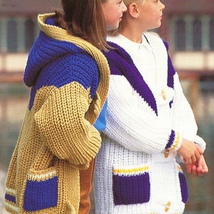 May include: Two girls wearing knitted cardigans with contrasting colour panels and pockets. The cardigan on the left is tan with blue and yellow stripes, and the cardigan on the right is white with purple and yellow stripes.