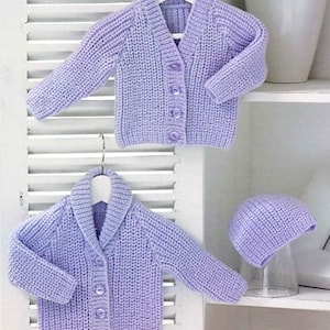 Puede incluir: Dos cárdigans de punto lavanda con cierres de botón y un gorro de punto lavanda a juego. Los cárdigans tienen una textura acanalada y un cuello.