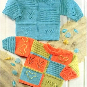 May include: Two knitted baby sweaters with colorful patchwork designs and embroidered hearts. The sweaters are laid out on a light brown surface.