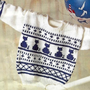 Könnte beinhalten: Weißer gestrickter Baby-Pullover mit einem blau-weißen Muster aus Katzen und Sternen.