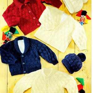 Puede incluir: Una colección de ropa de punto para niños, que incluye cárdigans rojos y azul marino, y jerséis y gorros color crema. Las prendas se exhiben sobre una superficie de madera amarilla, con soldaditos de juguete y formas geométricas.