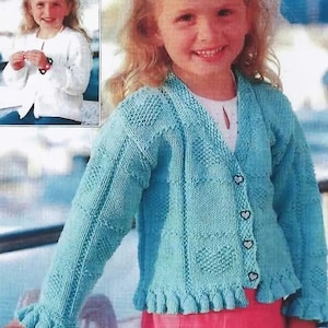 May include: A light blue knitted cardigan with a heart-shaped button closure. The cardigan has a ruffled hem and cuffs. The cardigan is worn by a child with long blonde hair.