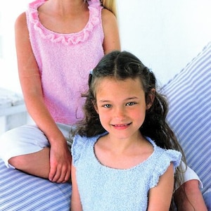 Könnte beinhalten: Zwei Mädchen tragen ärmellose Oberteile mit Rüschen. Das Mädchen vorne trägt ein hellblaues Oberteil und das Mädchen hinten trägt ein rosa Oberteil.