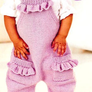 Può includere: Un bambino indossa una tuta di maglia lilla chiaro con tasche e spalline a balze, abbinata a una camicia bianca con colletto. La tuta ha un fiore decorativo sulle spalline. Il testo "TWO-BALL KNIT!" è in un cerchio viola.