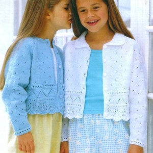 May include: Two girls wearing knitted cardigans. The girl on the left is wearing a light blue cardigan with a white trim. The girl on the right is wearing a white cardigan with a light blue trim. Both cardigans have a lace pattern.